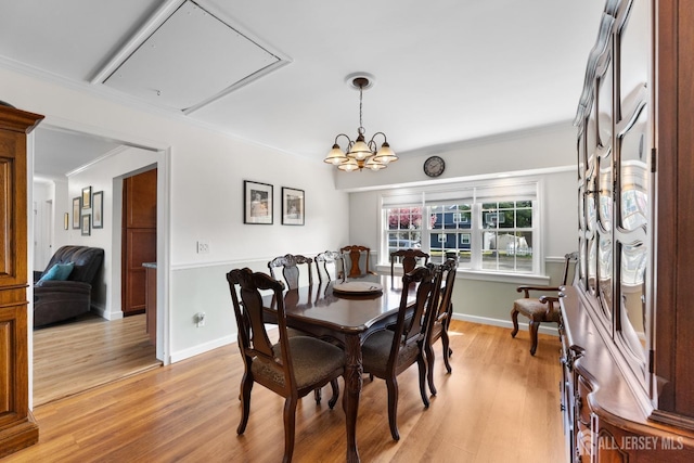 dining area featuring light wood-type flooring, ornamental molding, attic access, baseboards, and a chandelier