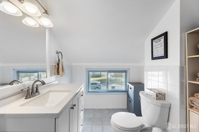 bathroom with lofted ceiling, toilet, plenty of natural light, vanity, and tile patterned floors