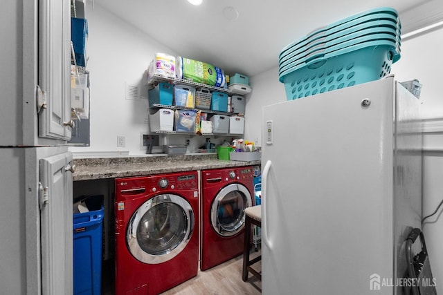clothes washing area featuring washer and dryer and light wood-style flooring