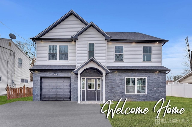 traditional home with a garage, fence, and aphalt driveway