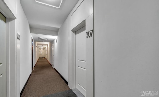 corridor with attic access, baseboards, and carpet flooring