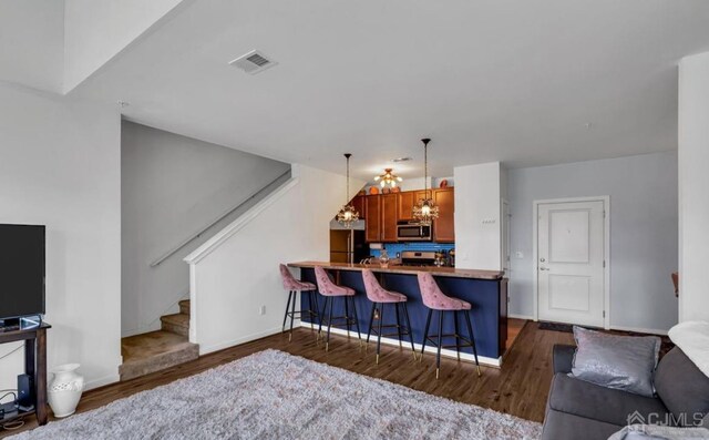 kitchen with stainless steel appliances, an inviting chandelier, kitchen peninsula, decorative light fixtures, and a breakfast bar