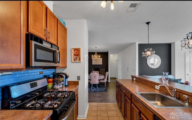 kitchen with pendant lighting, backsplash, sink, light tile patterned floors, and appliances with stainless steel finishes