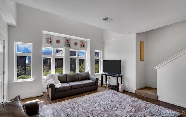 living room featuring a towering ceiling and dark hardwood / wood-style flooring