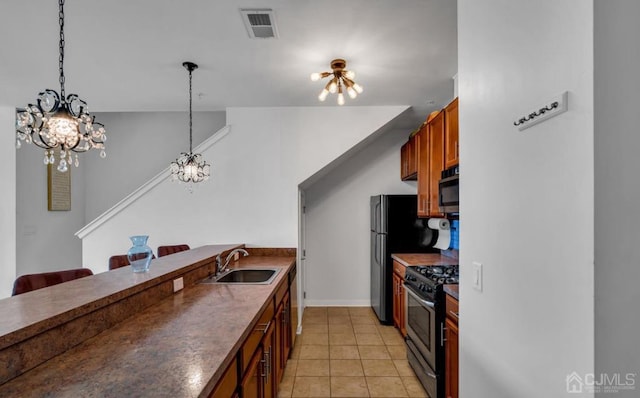 kitchen featuring sink, stainless steel gas range oven, an inviting chandelier, light tile patterned floors, and pendant lighting