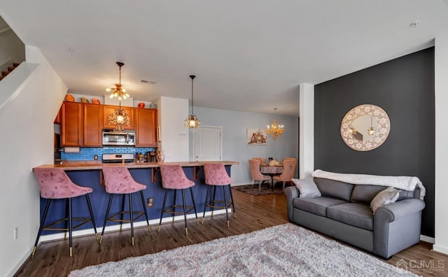 living room featuring dark wood finished floors, baseboards, and a notable chandelier