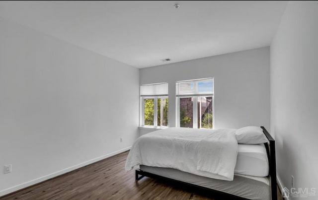 bedroom with wood finished floors, visible vents, and baseboards