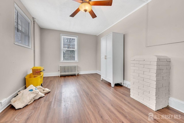 spare room featuring wood-type flooring, radiator, a textured ceiling, and ceiling fan