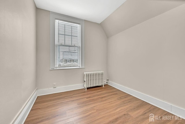 additional living space with lofted ceiling, radiator, and light hardwood / wood-style flooring