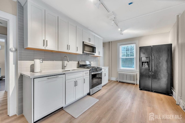 kitchen with white cabinetry, radiator heating unit, and stainless steel appliances