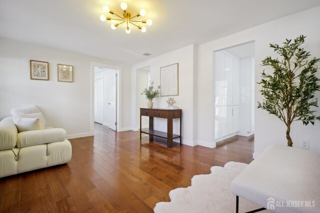 sitting room with dark wood-type flooring and an inviting chandelier