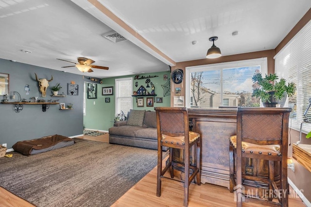 interior space with bar, ceiling fan, plenty of natural light, and wood-type flooring