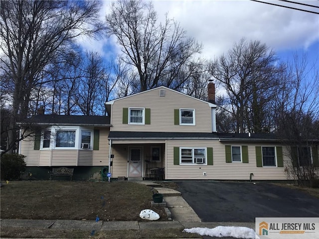 split level home with driveway and a chimney