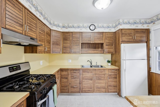 192 Lakeview Ave, Piscataway, NJ 08854 - kitchen featuring stainless steel range with gas stovetop, freestanding refrigerator, under cabinet range hood, brown cabinetry, and light countertops