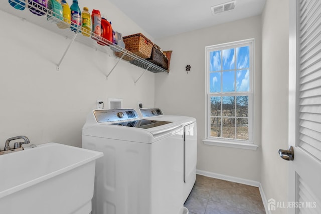 washroom featuring visible vents, a sink, separate washer and dryer, baseboards, and laundry area