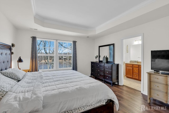 bedroom with dark wood finished floors, a raised ceiling, crown molding, and visible vents