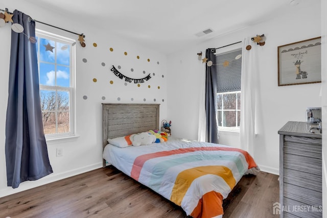 bedroom with visible vents, baseboards, and wood finished floors