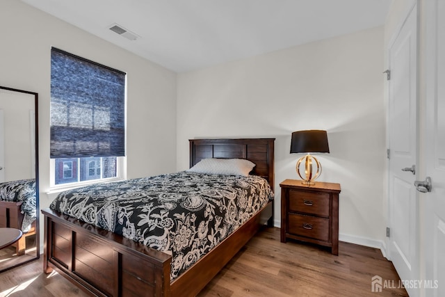 bedroom with visible vents, baseboards, and wood finished floors