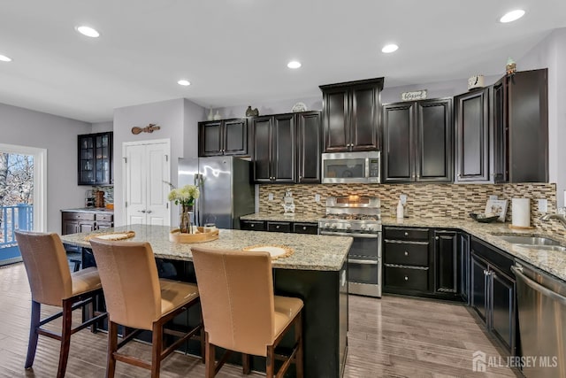 kitchen with tasteful backsplash, appliances with stainless steel finishes, a kitchen island, and a sink