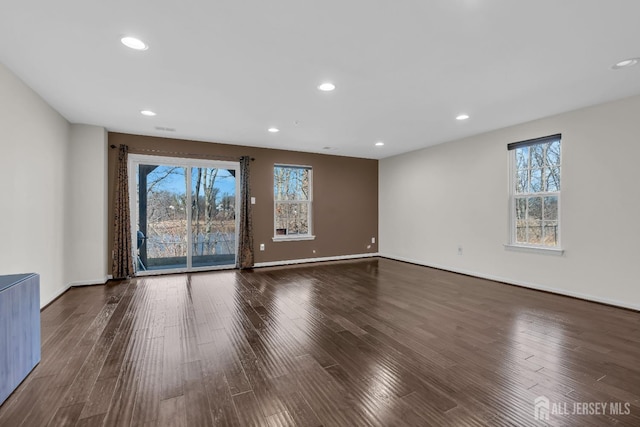 empty room with plenty of natural light, recessed lighting, baseboards, and wood finished floors