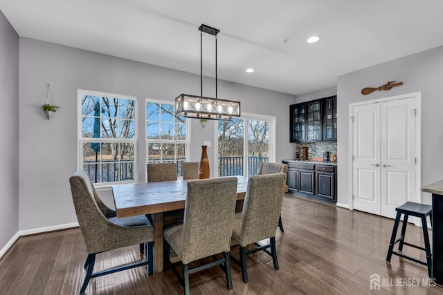 dining room with recessed lighting, baseboards, bar area, and dark wood finished floors