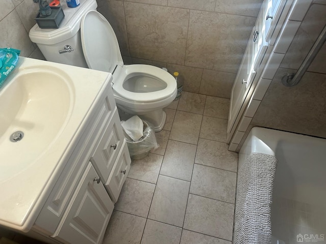 bathroom with toilet, vanity, tile walls, and tile patterned floors