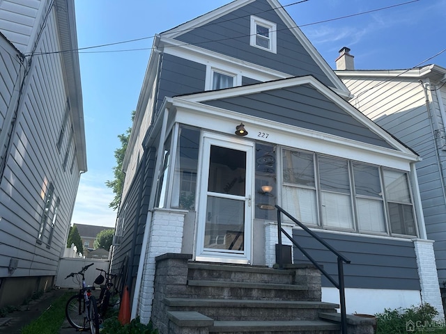 view of front of property with entry steps, brick siding, and fence