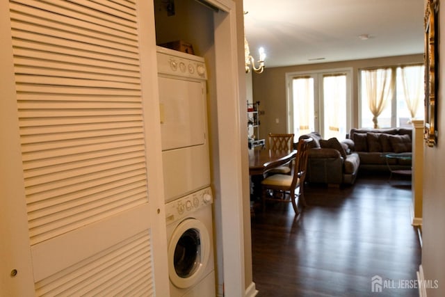 clothes washing area with wood finished floors, laundry area, and stacked washing maching and dryer