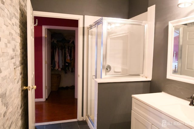 full bath featuring a shower stall, a walk in closet, and vanity