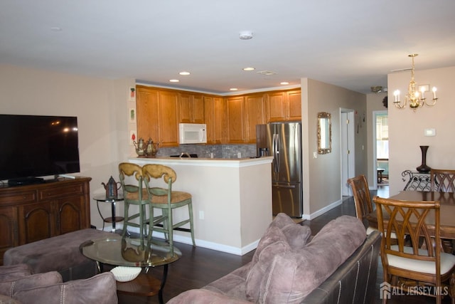 kitchen with backsplash, a peninsula, an inviting chandelier, stainless steel fridge with ice dispenser, and white microwave