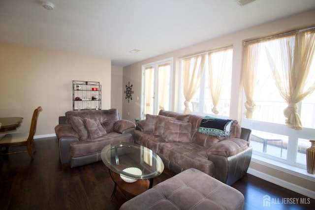 living room with a wealth of natural light, baseboards, and wood finished floors