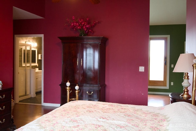 bedroom with wood finished floors, baseboards, and connected bathroom