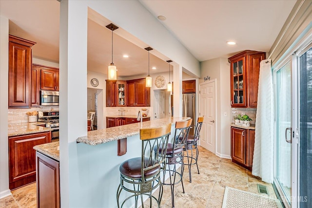 9 Sedgwick St, Jamesburg, NJ 08831 - kitchen with appliances with stainless steel finishes, tasteful backsplash, a breakfast bar area, light stone counters, and glass insert cabinets