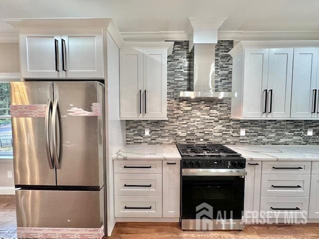 kitchen with light stone countertops, stainless steel fridge, range with gas stovetop, and white cabinets