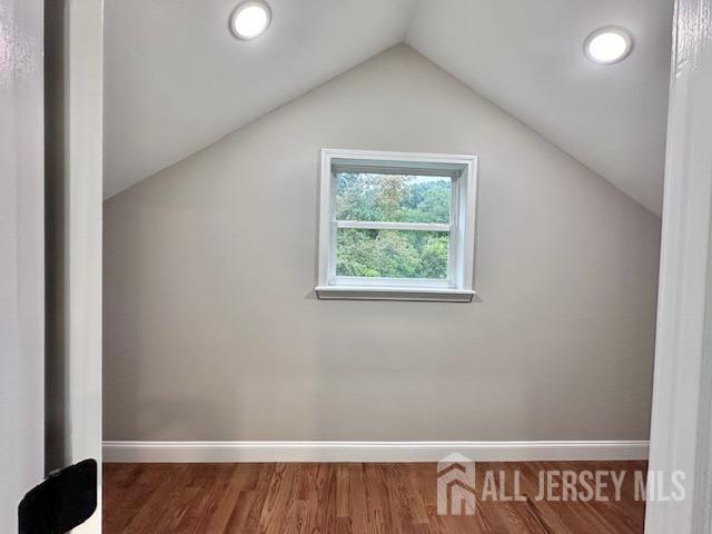 additional living space with hardwood / wood-style flooring and lofted ceiling