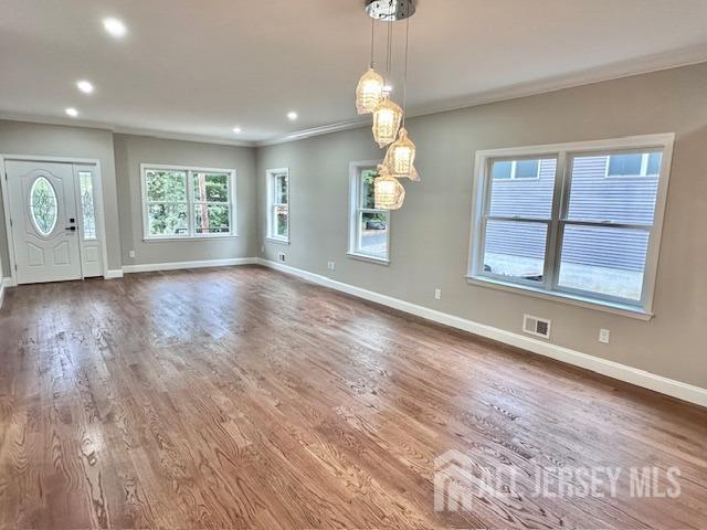 unfurnished dining area featuring ornamental molding and hardwood / wood-style floors