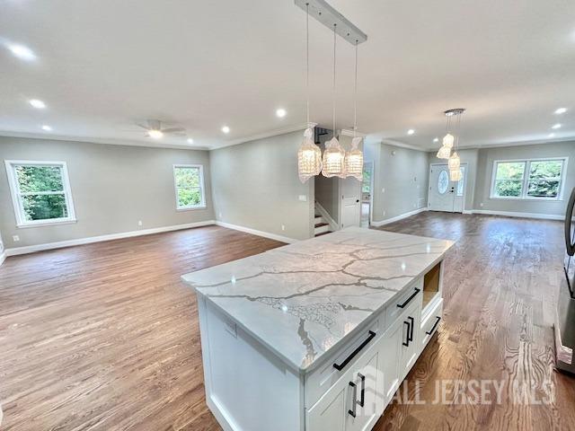 kitchen with white cabinetry, light stone countertops, a center island, and pendant lighting