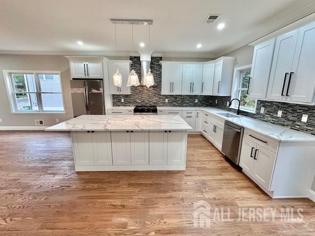 kitchen featuring a kitchen island, appliances with stainless steel finishes, pendant lighting, sink, and white cabinets