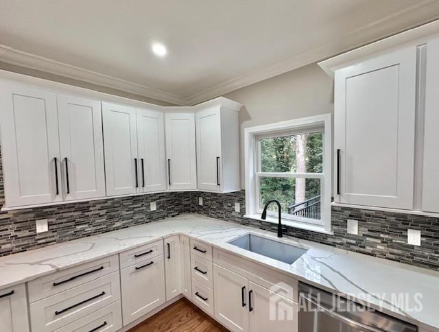 kitchen featuring dishwasher, light stone countertops, sink, and white cabinets