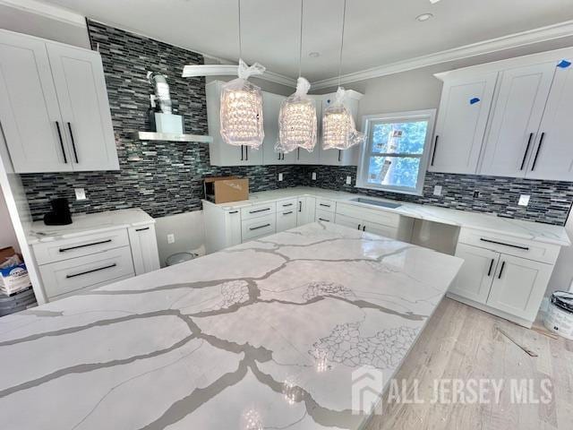 kitchen featuring hanging light fixtures, white cabinetry, and light stone countertops