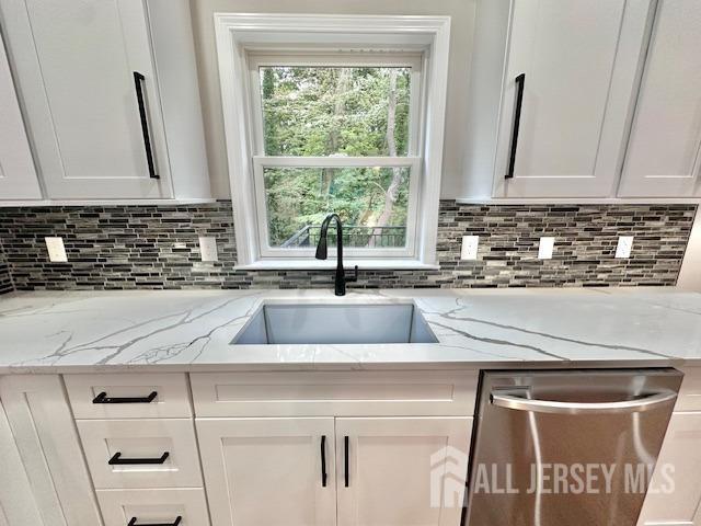 kitchen with sink, dishwasher, light stone counters, tasteful backsplash, and white cabinets