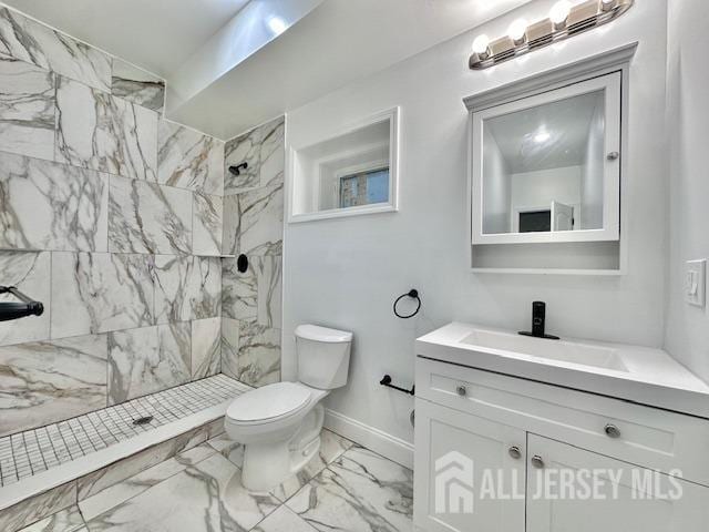 bathroom featuring a tile shower, vanity, and toilet