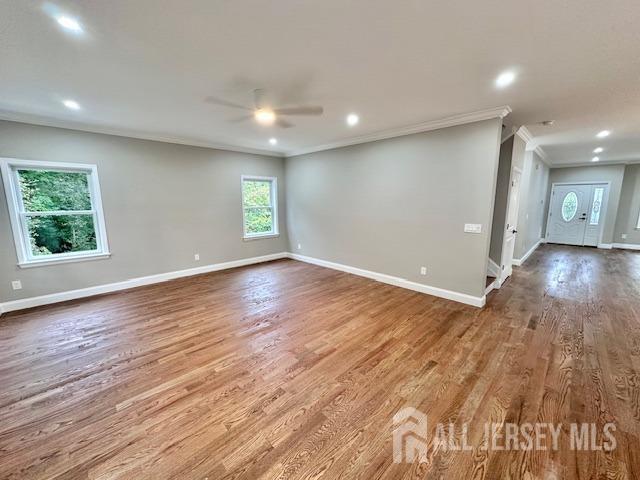 empty room with wood-type flooring, ornamental molding, and ceiling fan