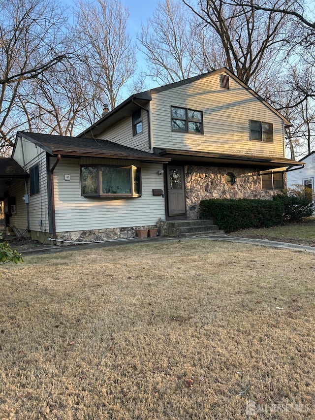 view of front of house with stone siding, a chimney, and a front lawn