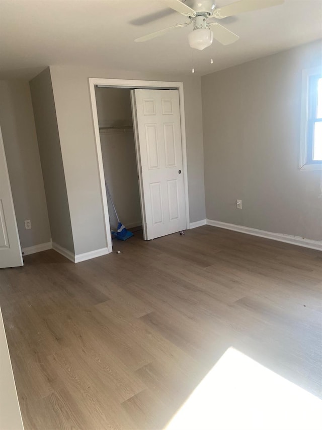 unfurnished bedroom with a ceiling fan, a closet, baseboards, and wood finished floors