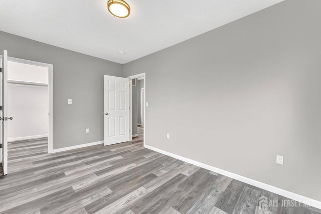 unfurnished bedroom with a closet, a walk in closet, and light hardwood / wood-style floors