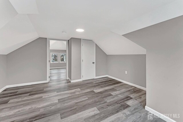 additional living space featuring lofted ceiling and hardwood / wood-style floors