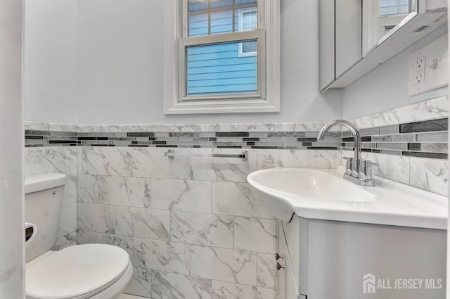 bathroom featuring toilet, tile walls, and vanity