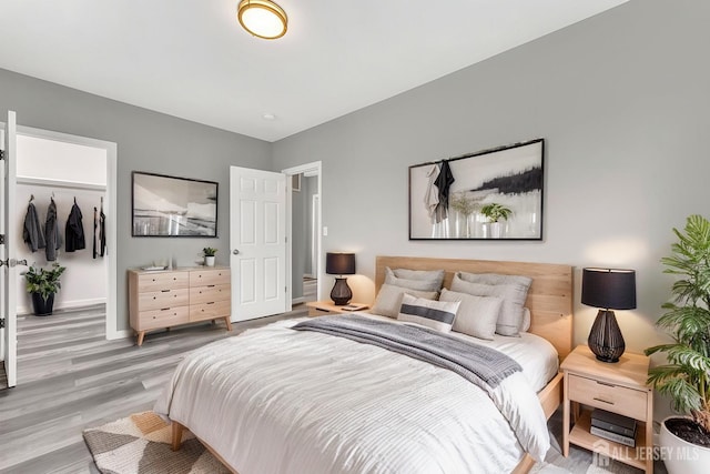 bedroom with light hardwood / wood-style flooring and a walk in closet