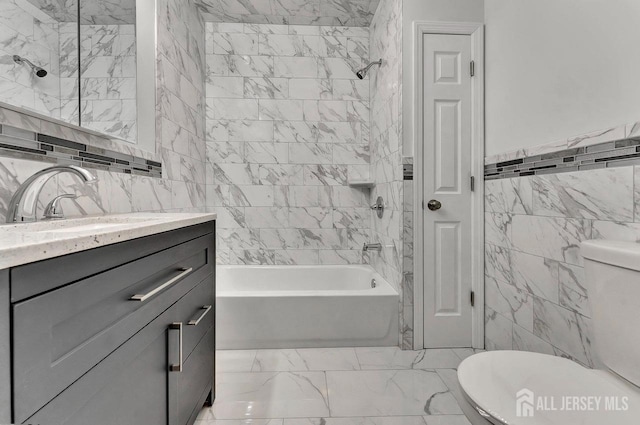 full bathroom with tile walls, tiled shower / bath combo, vanity, and toilet